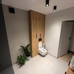 P.P.U.H Dariusz Rogowiec - Nowoczesna łazienka z drewnianą szafą w zabudowie, wiszącą toaletą z funkcją bidetu, roślinami doniczkowymi i oświetleniem punktowym.