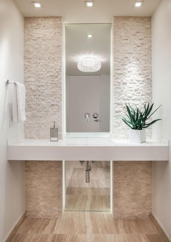 Nowoczesna łazienka z umywalką nablatową, lustrem z podświetleniem LED, ścianą wyłożoną dekoracyjną płytką imitującą kamień oraz rośliną doniczkową.