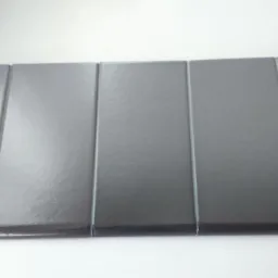 Pięć ciemnoszarych, błyszczących płytek ułożonych obok siebie, tworzących gładką powierzchnię. Widoczne delikatne refleksy światła na powierzchni płytek.