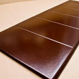 Brązowy parapet z konglomeratu, podzielony na segmenty, leżący na kartonowym podłożu.