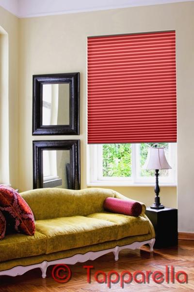 Czerwone plisy okienne w salonie z żółtą sofą i dwoma lustrami w czarnych ramach.