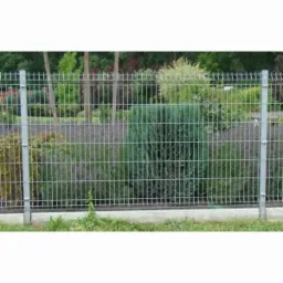 Panelowe ogrodzenie z metalowej siatki, osadzone na niskiej betonowej podmurówce, za którym widać zieleń ogrodu.