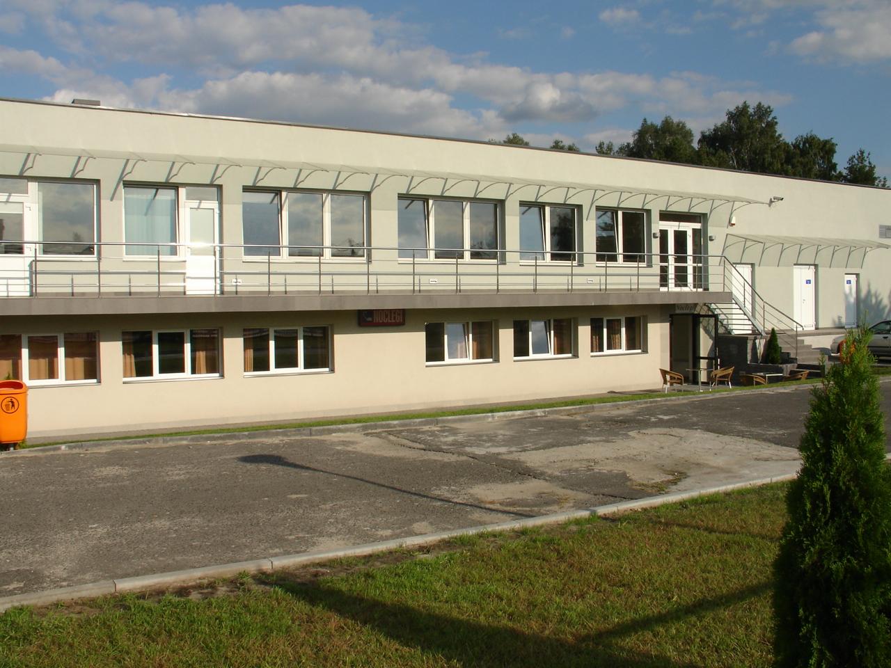 Dwupiętrowy budynek z balkonem i napisem 'Noclegi' w Biłgoraju, widoczny z zewnątrz, z elementami zieleni wokół.