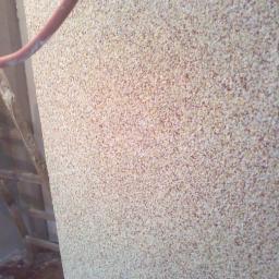 NAD-TEK usługi remontowo- budowlane - Nakładanie marmolitu na ścianę, widoczny fragment drabiny i przewód narzędzia.