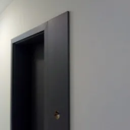 Szara ościeżnica drzwiowa po malowaniu, widoczna mała dziurka po klamce na tle jasnej ściany.