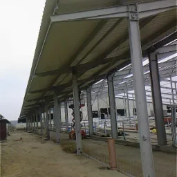 Konstrukcja stalowa hali w trakcie budowy w Świebodzinie, widoczne słupy, dach i podłoże gruntowe, w tle podnośnik koszowy.