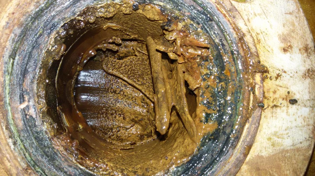 Zablokowany odpływ kanalizacyjny z widocznymi zanieczyszczeniami i rdzą. Wnętrze rury pokryte osadem. Ujęcie z bliska.