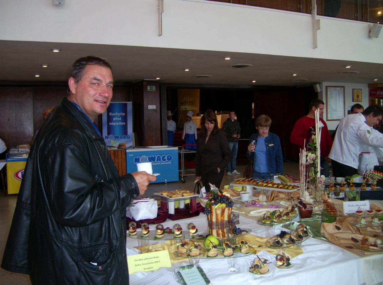 Degustacja potraw na stole podczas wydarzenia. Osoby w tle, mężczyzna w czarnej kurtce na pierwszym planie. Catering z potrawami.