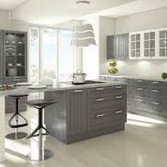 Nowoczesna kuchnia w odcieniach szarości z wyspą, minimalistycznym oświetleniem i dużym oknem w tle.