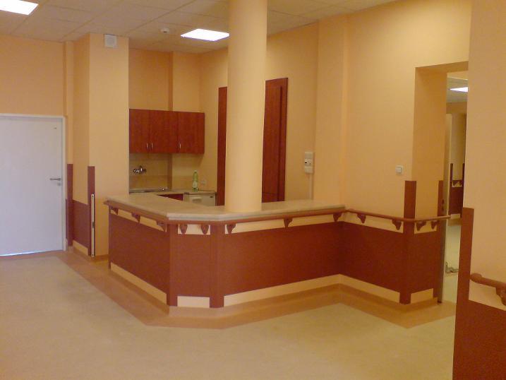 Wnętrze nowo wykończonego pomieszczenia z elementami instalacji elektrycznej: gniazdko, oświetlenie sufitowe, zabudowa meblowa z podłączeniem do instalacji wodno-kanalizacyjnej.