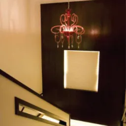 Klatka schodowa z czerwonym, ozdobnym żyrandolem nad podświetlonym stopniem, widok z góry.