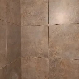 Beżowe, matowe płytki ceramiczne na ścianie, ułożone równo z wąską fugą, widok z bliska na narożnik ściany.