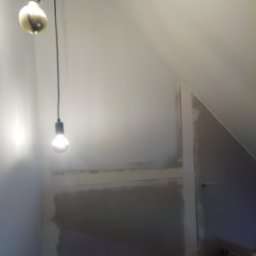 Flis Servis - Poddasze w trakcie remontu, ściany przygotowane do malowania, widoczne dwie wiszące żarówki bez kloszy.