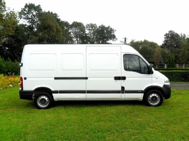 Biały, dostawczy bus Renault Master sfotografowany z boku na trawiastym terenie, widoczne detale karoserii i opon.