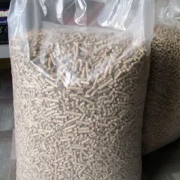 Duży, przezroczysty worek wypełniony po brzegi jasnymi pelletami, widoczny drugi, częściowo zasłonięty worek w tle.