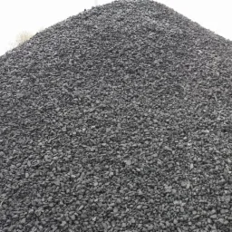 Góra ekogroszku o nieregularnych kształtach, sfotografowana w pochmurny dzień, z widocznymi drobnymi kamyczkami i pyłem węglowym.