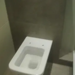 Wisząca miska WC bez deski, szare płytki na ścianie i podłodze, podtynkowy stelaż z przyciskami spłukiwania