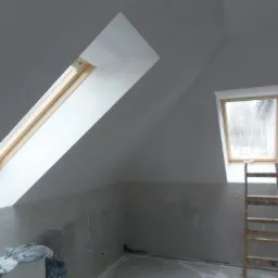 Poddasze w trakcie adaptacji w Warszawie, widoczne dwa okna dachowe, ściany przygotowane do malowania, drabina oparta o ścianę, widoczne niedoskonałości ścian przed wykończeniem.