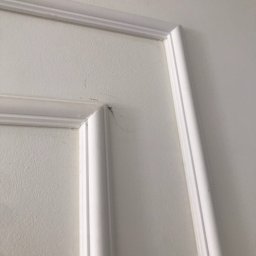 Crado - Fragment białej ściany z dekoracyjnym, profilowanym obramowaniem, widoczne drobne zabrudzenia w rogu.