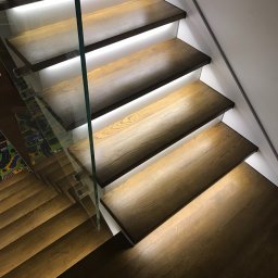 Crado - Schody drewniane z podświetleniem LED i szklaną balustradą, widok z góry, nowoczesny design