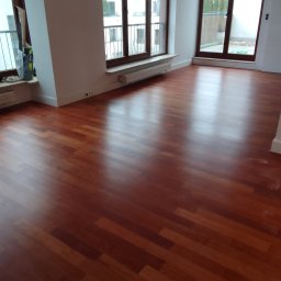 Szlif-Pol Mirosław Lis - Polakierowana, parkietowa podłoga w odcieniach brązu, ułożona w jodełkę, w jasnym pokoju z dużymi oknami w Warszawie.