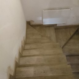 Perfect finish Mirosław Grochola - Wykończone schody wewnętrzne z płytek imitujących drewno, widok z góry. Na ścianie widoczny grzejnik.