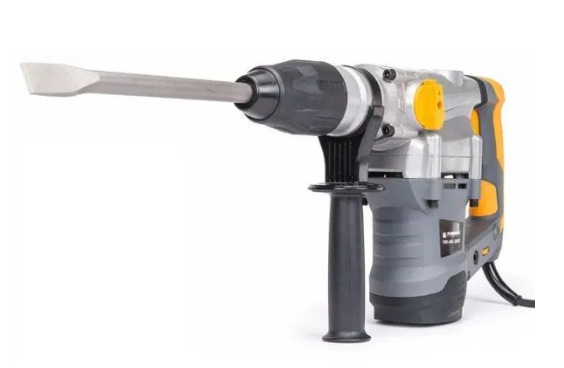 Elektryczny młot udarowy z dłutem płaskim, model z szaro-żółtymi akcentami, uchwyt pomocniczy, widok z boku na białym tle.