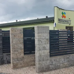 Ekspozycja fragmentów ogrodzeń: betonowe słupki z poziomymi przęsłami metalowymi w kolorze grafitowym, różne odcienie betonu, w tle budynek firmy Siatkomet.