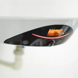 Fragment białego kotła gazowego z czarnym panelem sterowania, wyświetlacz LED pokazuje temperaturę 60 stopni Celsjusza, widoczne rury doprowadzające wodę.