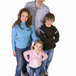 Uśmiechnięta rodzina: ojciec w jasnej koszuli, matka w błękitnym swetrze, syn ze skrzyżowanymi rękami i dwie córki w dżinsach i swetrach, pozują na białym tle.