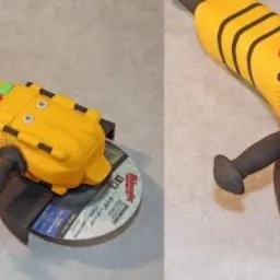 Żółta, nietypowa szlifierka kątowa z czarnymi paskami i wtyczką, wykonana w technologii addytywnej. Widoczne detale i kolorystyka. Prezentacja produktu.