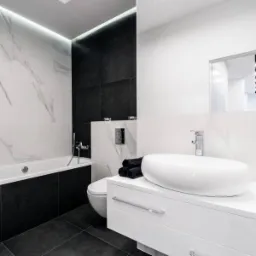 Nowoczesna łazienka w czarno-białej kolorystyce z wanną, umywalką nablatową i podświetleniem LED podsufitowym.