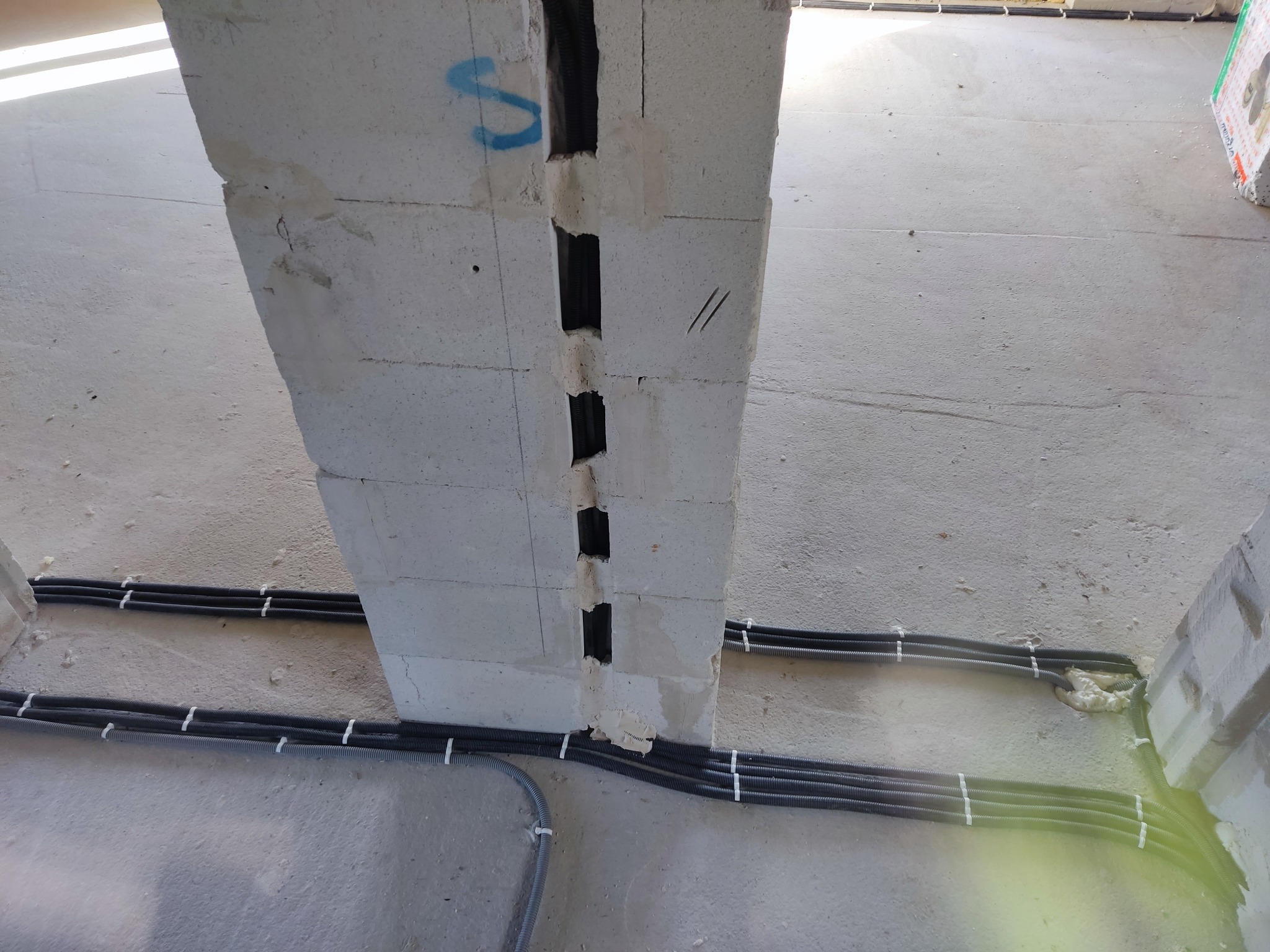 Wykute bruzdy w ścianie z betonu komórkowego, w których umieszczono rury karbowane z przewodami. Kable przymocowane do ściany za pomocą uchwytów.