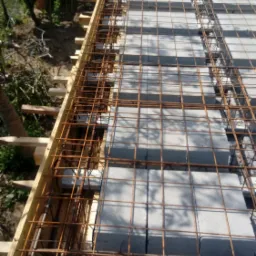 Wiązanie zbrojenia i szalunku pod wylewkę na stropie z pustaków szalunkowych, widok z góry w słoneczny dzień.