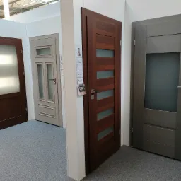 Ekspozycja trzech modeli skrzydeł w odcieniach brązu i szarości, z przeszkleniami, prezentowanych na jasnym stoisku targowym z szarą wykładziną.