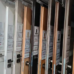 Ekspozycja różnych modeli drzwi wewnętrznych w sklepie, widoczne ceny i oznaczenia producentów, prezentacja klamek i zamków.