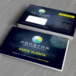 Karty klienta 'Prostor Chemia Gospodarcza' ułożone w stos, prezentujące zasady programu lojalnościowego i korzyści z zakupów. Ciemne tło kart z jasnymi napisami.
