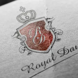 Elegancki, ręcznie rysowany herb z literą B i koroną, na papierze o wyraźnej fakturze, z napisem 'Royal Day' w ozdobnej czcionce.