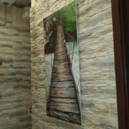 Ściana wykończona kamieniem dekoracyjnym z wkomponowanym obrazem mostu wiszącego i punktowym oświetleniem.