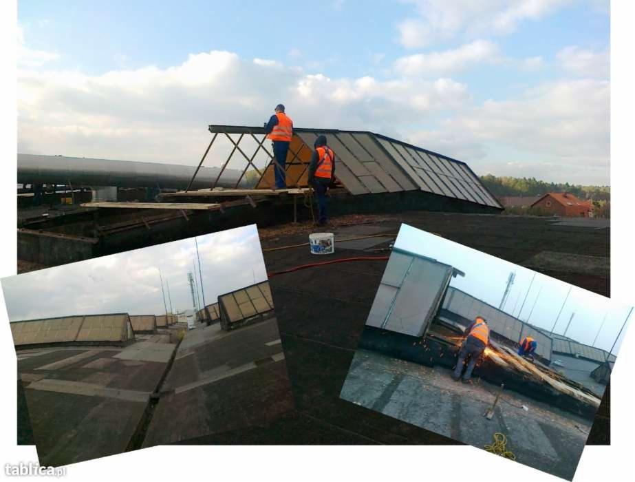 Prace dekarskie na dachu płaskim z świetlikami: dekarze w kamizelkach, spawanie konstrukcji, widok na okolicę. Ujęcie z góry, w dzień, z widocznymi narzędziami.