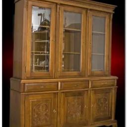 Trzydrzwiowy, dębowy kredens z przeszkloną nadstawką i rzeźbionymi drzwiami, widoczne wnętrze z półkami, oświetlenie studyjne.