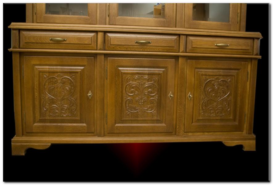 Drewniany kredens z trzema szufladami i trzema szafkami, zdobiony rzeźbionymi ornamentami kwiatowymi i sercowymi na frontach szafek, wykończony w ciepłym, miodowym odcieniu.