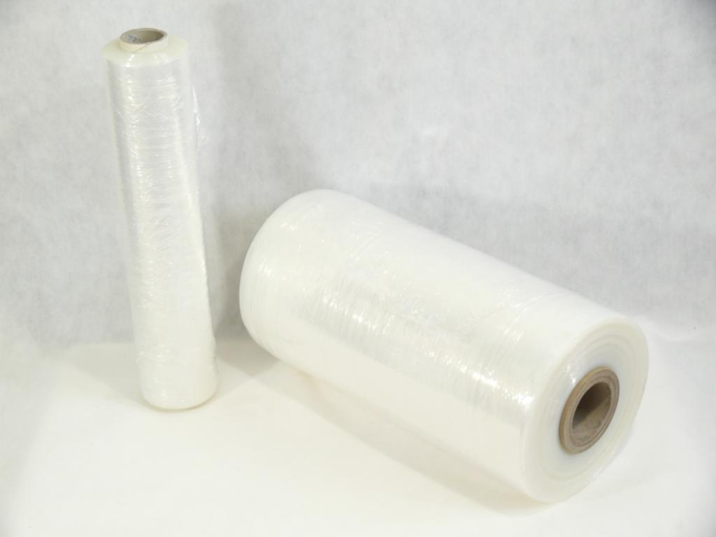 Dwie rolki przezroczystej folii stretch na białym tle. Jedna rolka stoi pionowo, druga leży poziomo, ukazując tekturowy rdzeń.