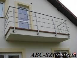 Balkon z nowoczesną metalową barierką o minimalistycznym designie, mocowaną do elewacji budynku. Widoczne detale mocowań i subtelne odbicia światła na metalu.