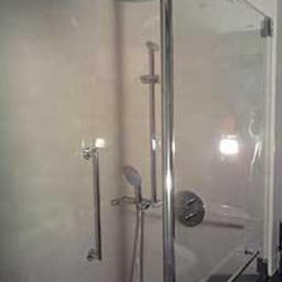 Mag-Instal - Kabina prysznicowa z deszczownicą i chromowanymi elementami wykończeniowymi, widok z boku, jasne płytki na ścianach.