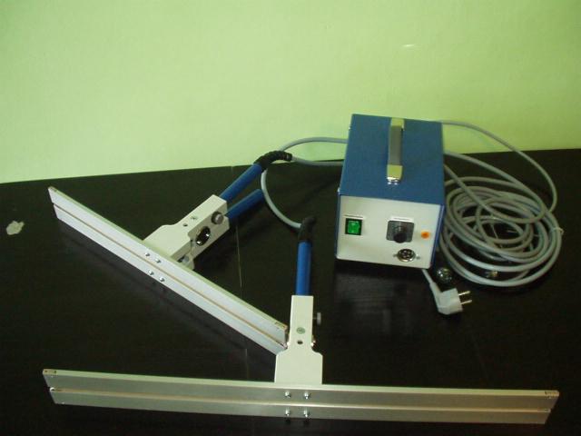 Zgrzewarka impulsowa do folii z niebieskim zasilaczem i kablem na czarnym blacie.