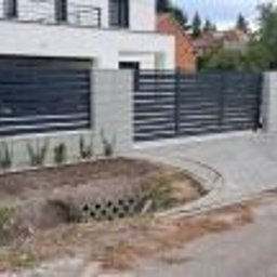 ABG MATERIAŁY Bartosz Lewandowski - Nowoczesne ogrodzenie panelowe z poziomych profili w kolorze antracytowym, osadzone na betonowych słupkach, z kostką brukową na podjeździe i młodymi roślinami u podstawy.