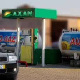 Czarny samochód Audi na stacji paliw z dystrybutorem i zbiornikami autogazu oznaczonymi logo AXAN i motywem słonecznika.