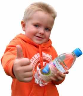 Uśmiechnięty chłopiec w pomarańczowej bluzie pokazuje kciuk w górę, trzymając butelkę wody mineralnej.