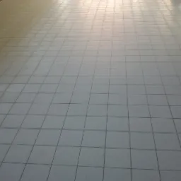 Jasnoszara podłoga wyłożona kwadratowymi płytkami gresowymi z ciemniejszą fugą, widok z perspektywy podłogi.